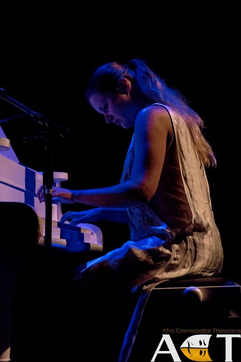 En af pianisterne spiller forestillingens incidentalmusik i Købmanden i Venedig under blåt scenelys ved klaveret.