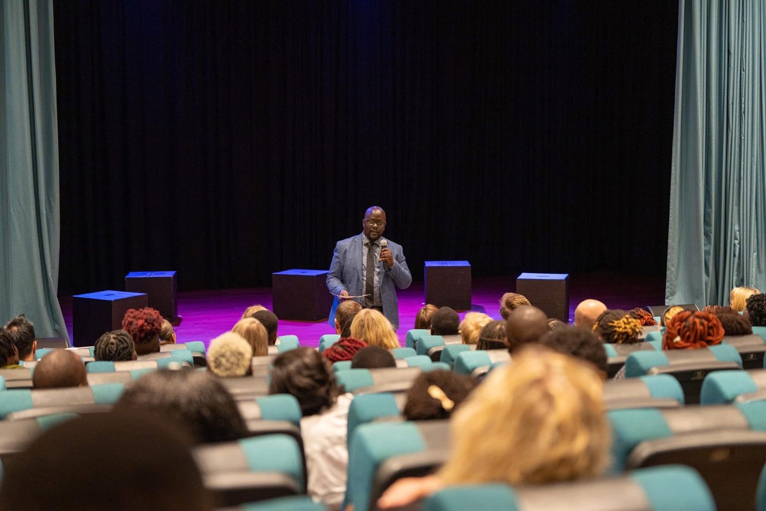 Michael Omoke taler til publikum ved åbningen af forestillingen.